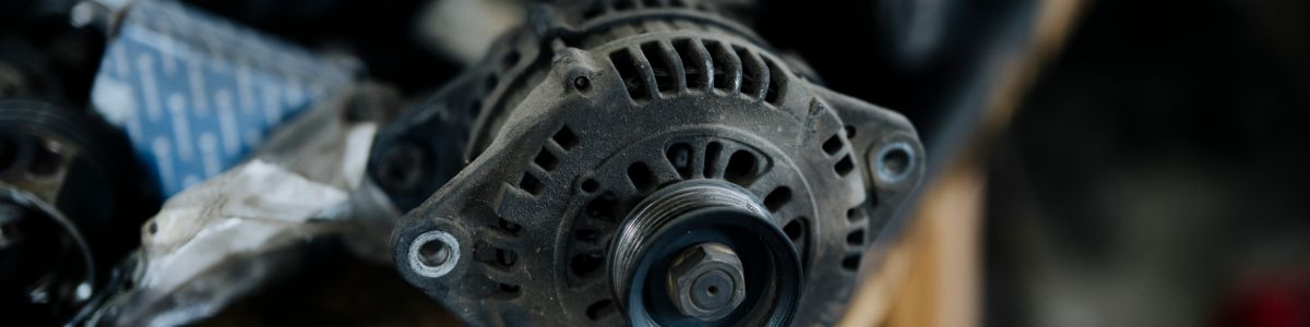Close-up of a used alternator lying beside packaging in a workshop